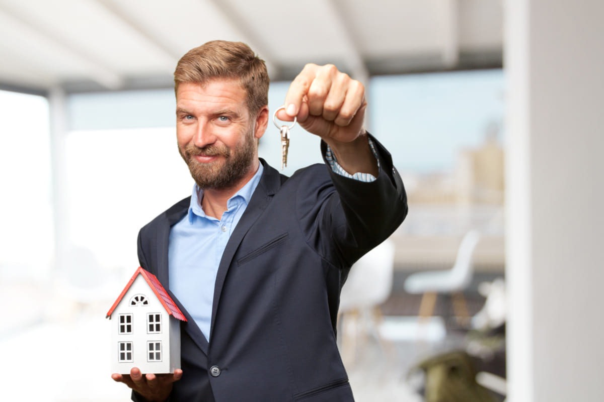 A man holding a model home and keys