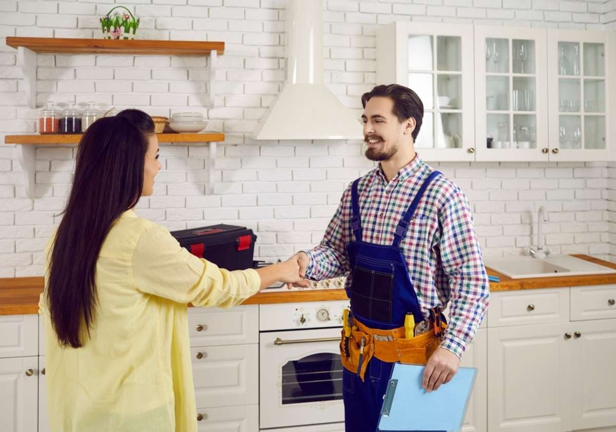 A woman shakes hands with a professional repairman, property management company Indianapolis concept
