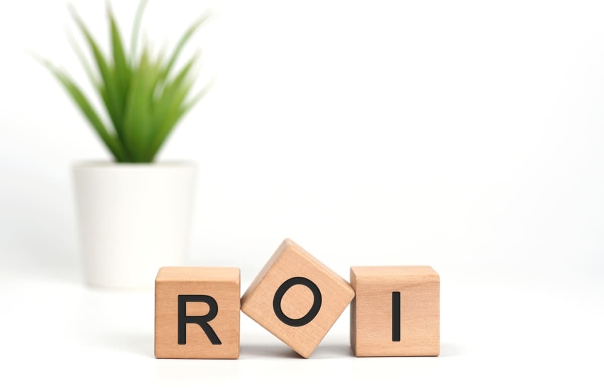 Block letters that spell ROI in front of a plant