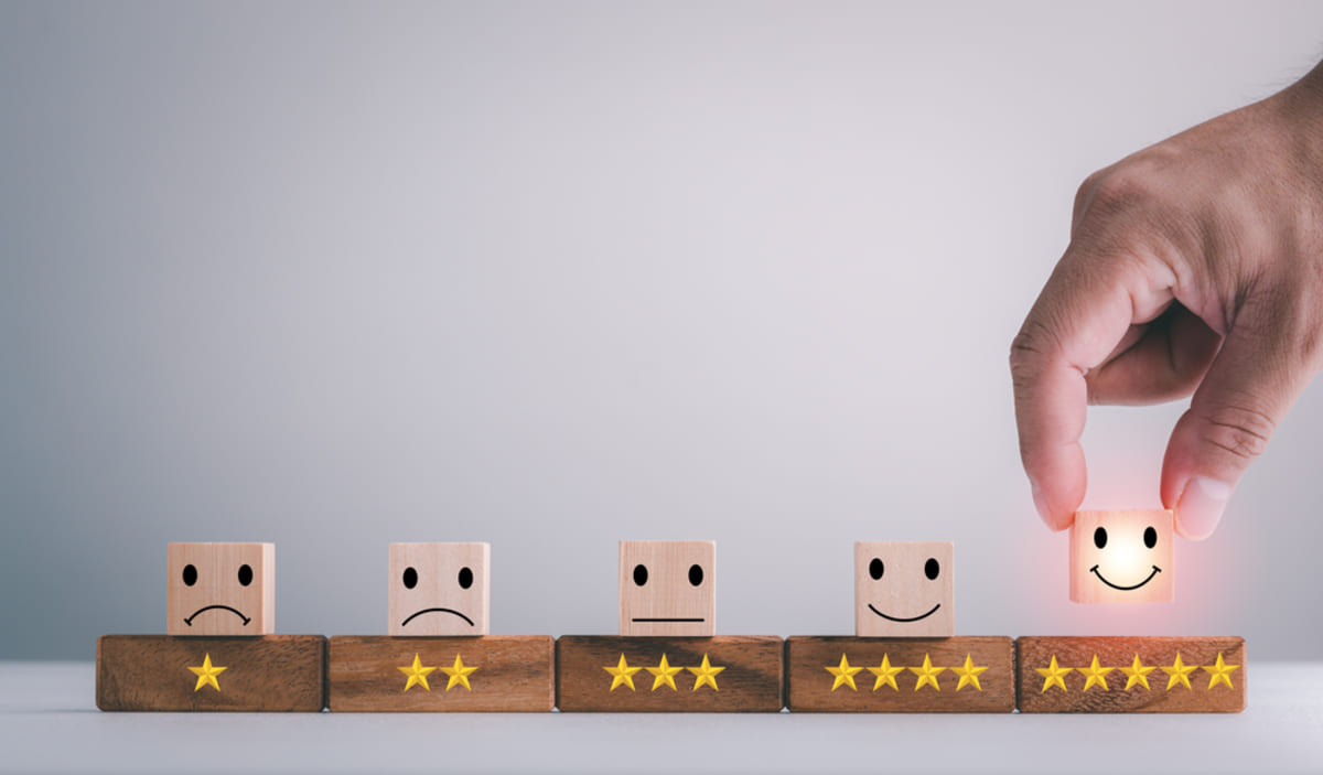 Faces on wooden blocks representing good and bad reviews, choosing the right property manager concept.