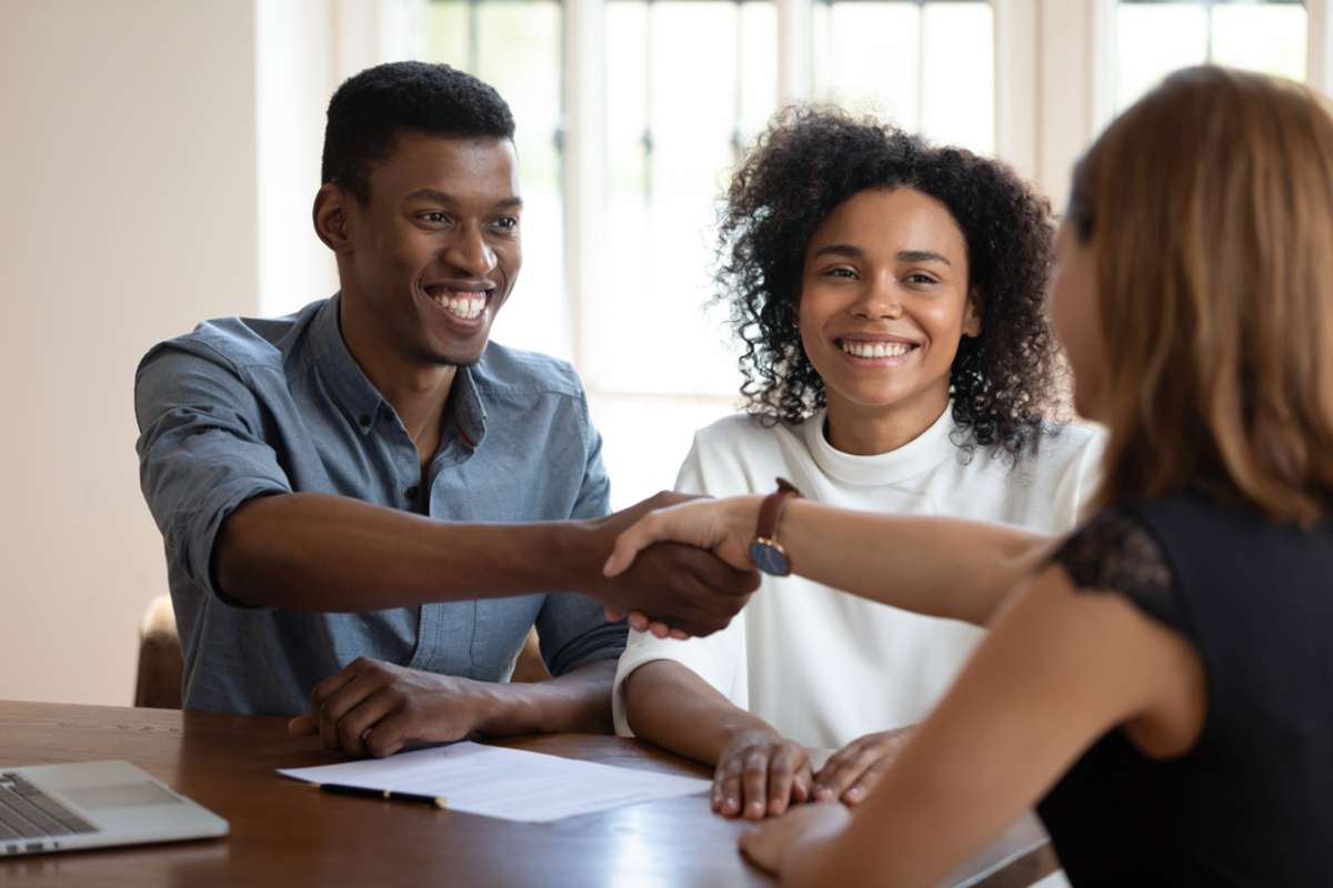 Happy young african american married couple clients shaking hands with financial advisor-1