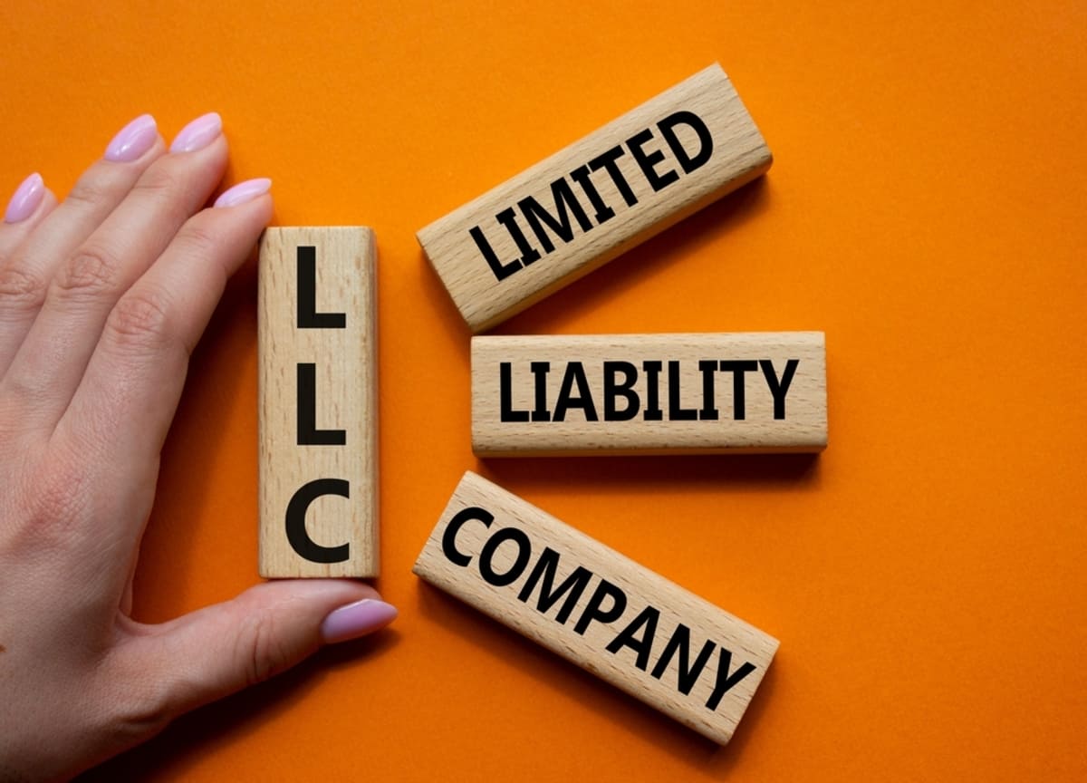 Wooden blocks that say LLC and Limited Liability Company in front of an orange background