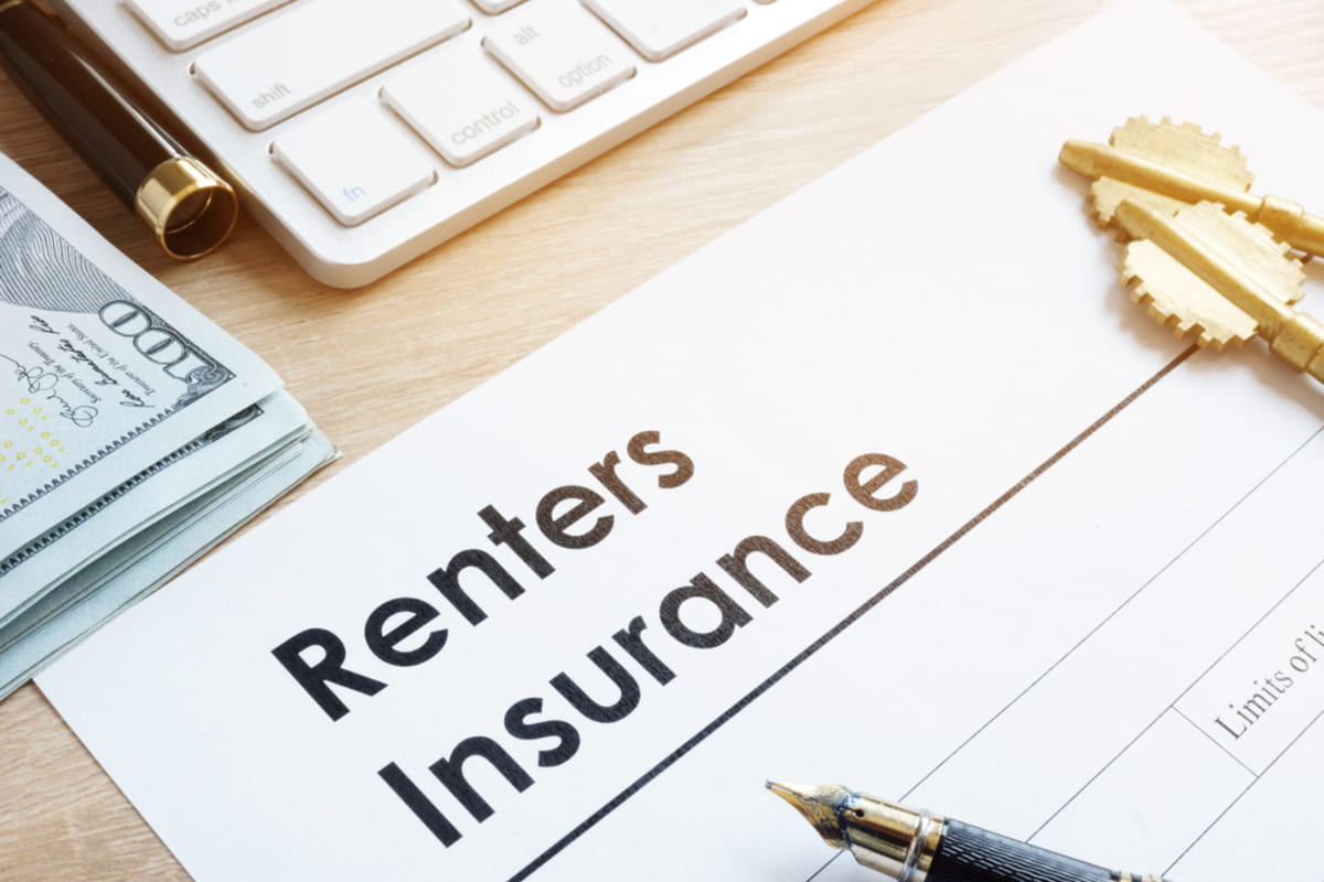 A document that says renters insurance next to keys and cash