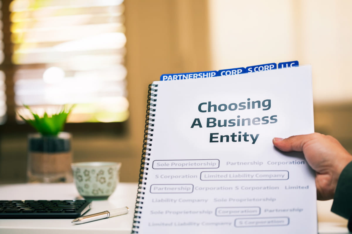 A journal labeled Choosing a Business Entity on a desk, rental property LLC concept