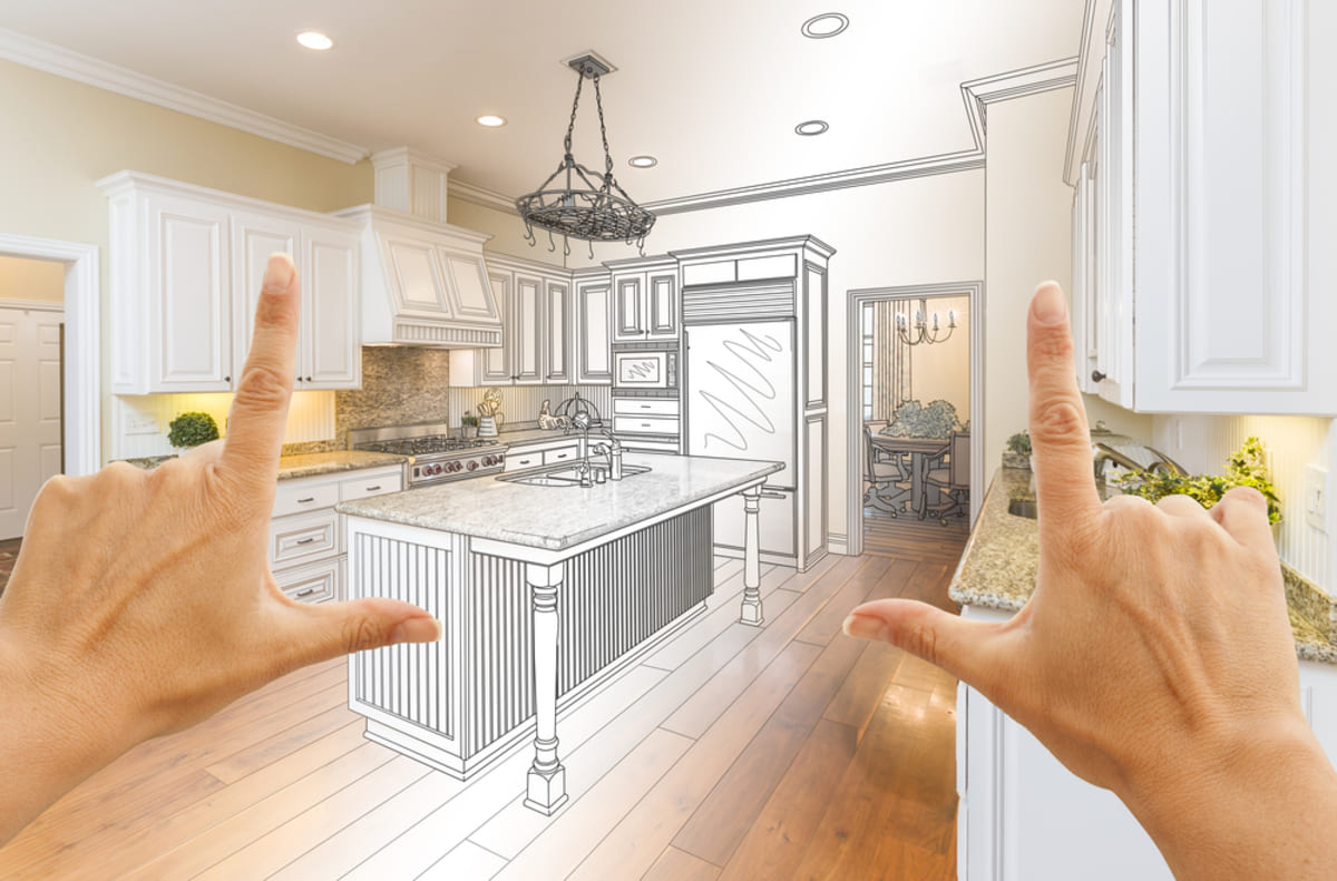 Person's hands framing a new sketch of the kitchen, rental property upgrades concept.