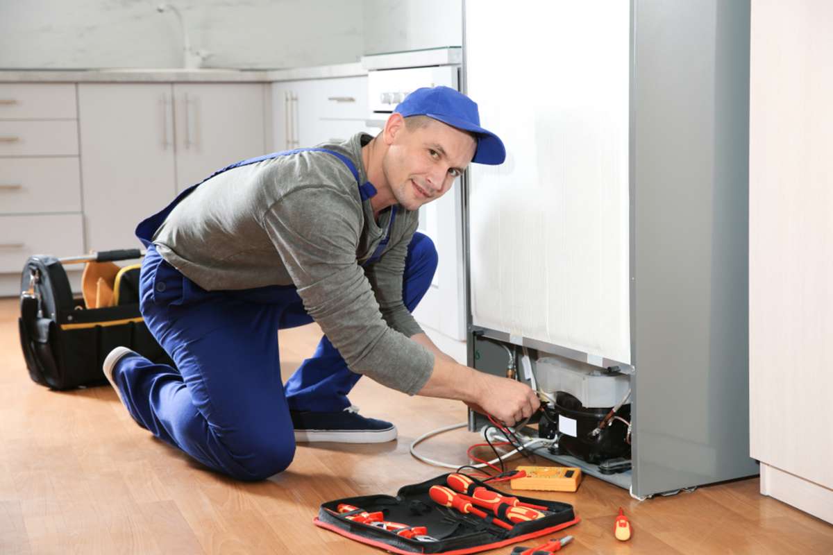 Professional maintenance technician repairs a refrigerator