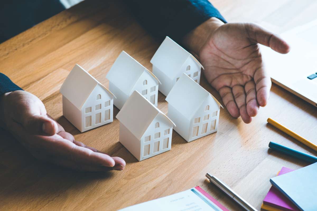 Small white houses on a table represent how to get into real estate investing