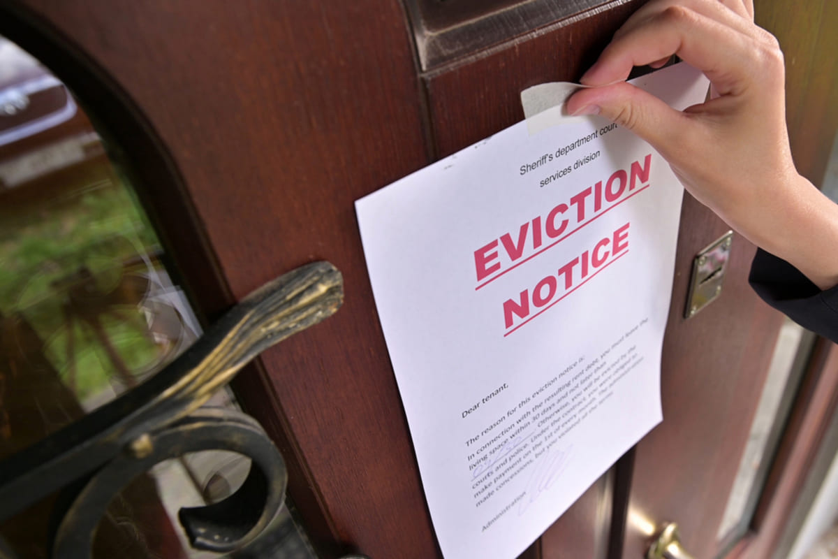 Someone putting a tenant eviction notice on a tenant's door, tenant eviction concept.