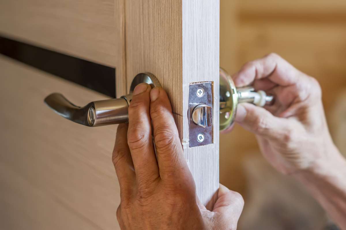 closeup of worker's hands installing new door locker