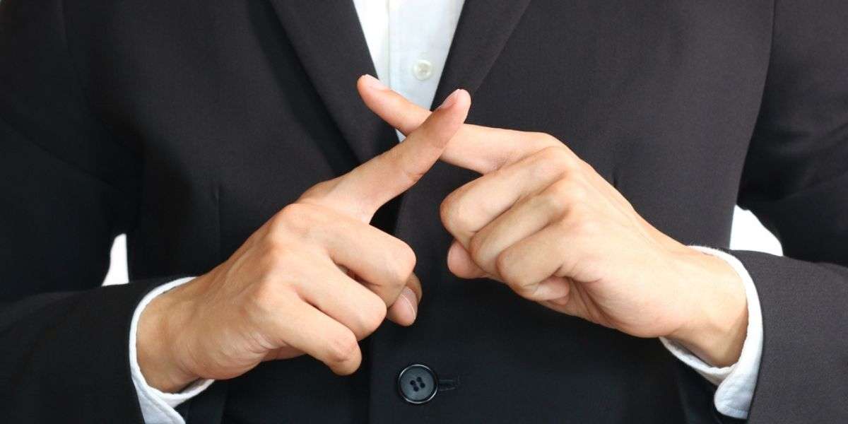 Asian businessman in black suit cross fingers to say no