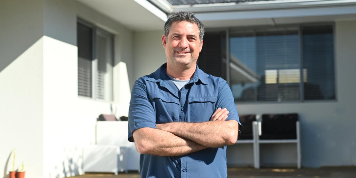 Confident man smiling outside his house, residential property owner